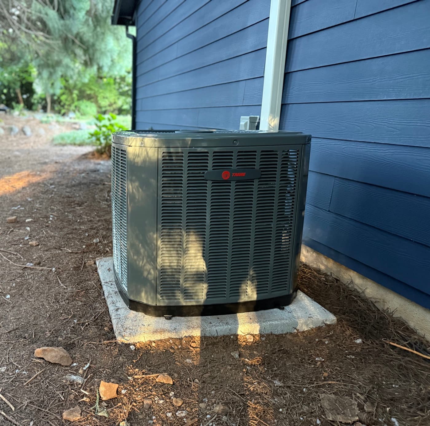 A newly installed Trane outdoor AC condenser beside a blue Portland-area home.